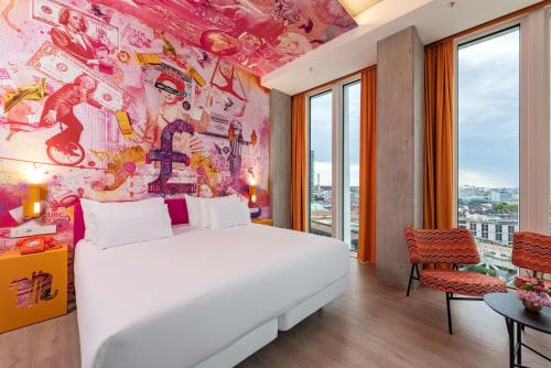 a bedroom with a white bed and a colorful wall at nhow Frankfurt in Frankfurt/Main