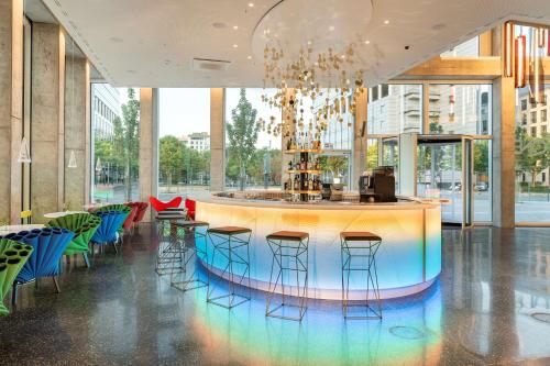a lobby with a bar with stools and chairs at nhow Frankfurt in Frankfurt/Main