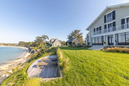une maison avec une passerelle en bois à côté de la plage dans l'établissement Villa Émeraude -Maison d'exception-Piscine-Jacuzzi, à Saint-Malo