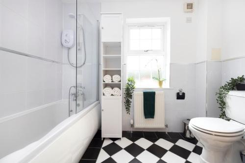 a white bathroom with a toilet and a checkered floor at JOIVY Greenknowes Cottage with Hot Tub & Fireplace in Kelty