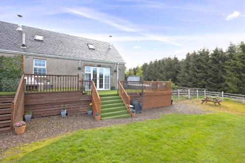 a house with a large deck with stairs and a yard at JOIVY Greenknowes Cottage with Hot Tub & Fireplace in Kelty