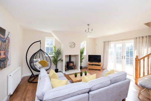 a living room with a couch and a tv at JOIVY Greenknowes Cottage with Hot Tub & Fireplace in Kelty