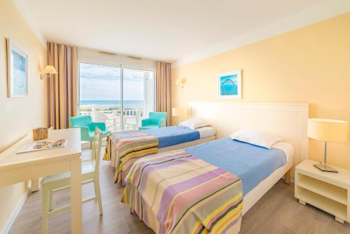 a hotel room with two beds and a table and chairs at Lagrange Vacances L’Estran in Les Sables-dʼOlonne