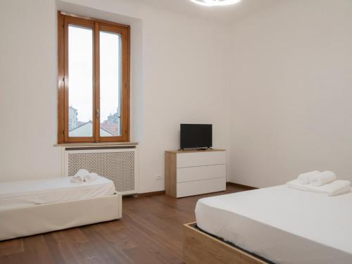 a white room with two beds and a television at I-Host Apartment - Cesarotti 2 in Milan