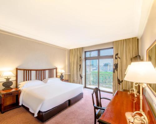 a bedroom with a bed and a desk and a window at Hyatt Regency Harare The Meikles in Harare