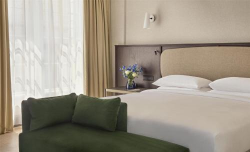 a bedroom with a bed and a couch in front of a window at Hyatt Regency London Blackfriars in London