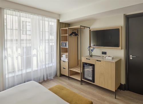 a bedroom with a bed and a tv and a window at Hyatt Regency London Blackfriars in London