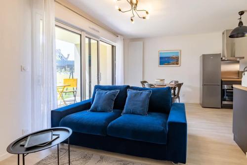 un salon avec un canapé bleu et une table dans l'établissement L'Equinoxe, T2 de plain-pied dans résidence neuve., à Saint-Malo