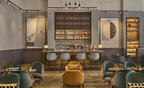 a restaurant with a bar with chairs and tables at Hyatt Regency London Blackfriars in London