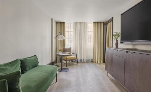 a living room with a green couch and a table at Hyatt Regency London Blackfriars in London