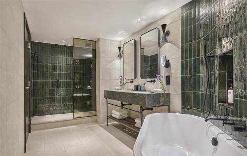 a bathroom with a tub and a sink and mirror at Hyatt Regency London Blackfriars in London