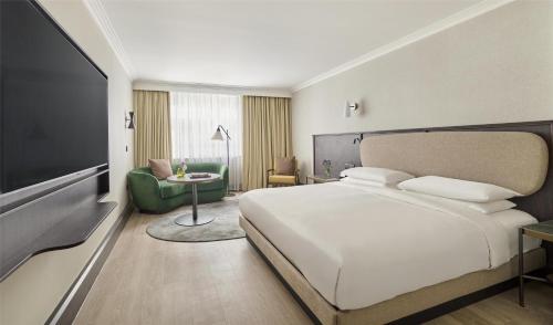 a bedroom with a white bed and a green chair at Hyatt Regency London Blackfriars in London