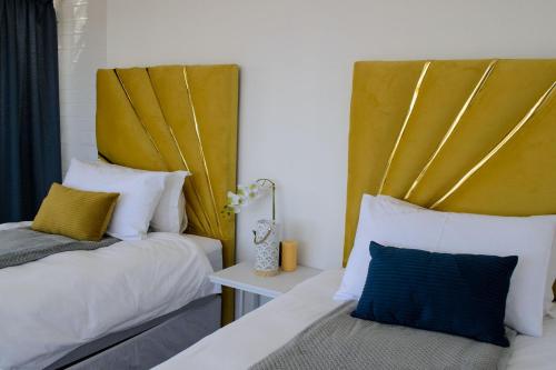 a bedroom with two beds and a yellow headboard at The View Apartment 5 in Lüderitz