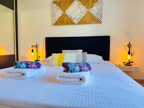 Un dormitorio con una gran cama blanca con toallas. en Appartement l'étang Salé Les Bains, en Étang-Salé