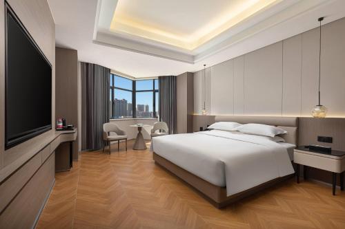 a hotel room with a bed and a television at Ramada by Wyndham Urumqi Midong in Ürümqi