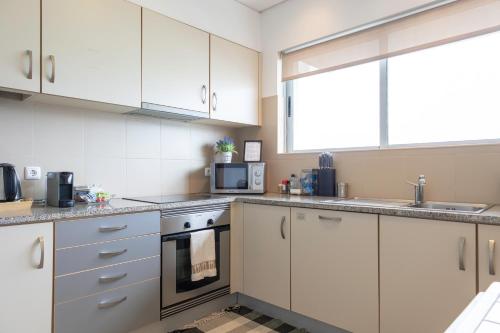 a kitchen with white cabinets and a microwave at Paim Apartment in Ramalho