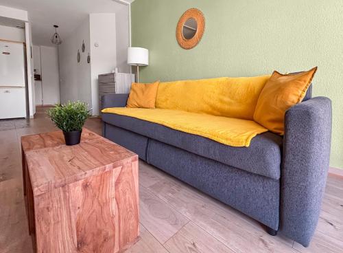 un canapé bleu avec des coussins jaunes dans un salon dans l'établissement T2 cosy avec terrasse & parking à 2 pas du port, à La Ciotat