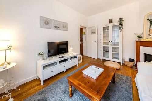 un salon avec une télévision et une table basse dans l'établissement L'Aparté, bel appartement lumineux avec 1 chambre, à Rennes