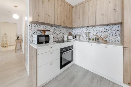 une cuisine avec des armoires blanches et un micro-ondes dans l'établissement L'Odyssée - Bel appartement -Terrasse/Parking, à Vannes