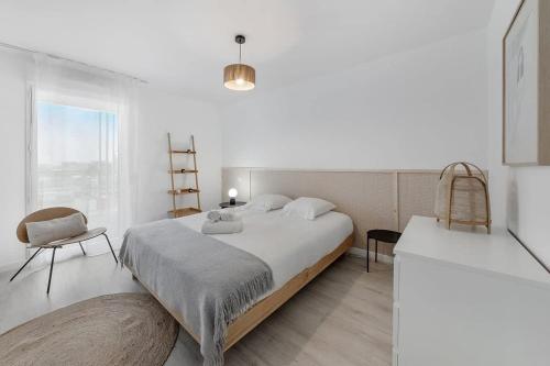 une chambre blanche avec un grand lit et une chaise dans l'établissement L'Odyssée - Bel appartement -Terrasse/Parking, à Vannes