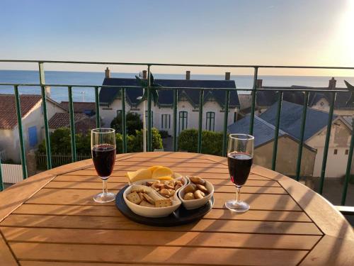 - une table avec un bol de nourriture et 2 verres de vin dans l'établissement Superbe duplex accès et vue mer, garage, linge fourni, à Saint-Hilaire-de-Riez