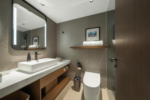 a bathroom with a sink and a toilet and a mirror at Atour Hotel Chengdu Taikoo Li Riverside in Chengdu