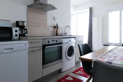 une cuisine avec une machine à laver et une table dans l'établissement souplex sur le port des sables pour 4 personnes, à Les Sables-dʼOlonne