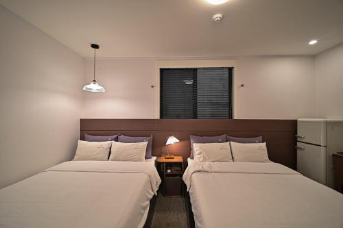 a room with two beds and a nightstand between them at 호텔 공감공간 부산역점 in Busan