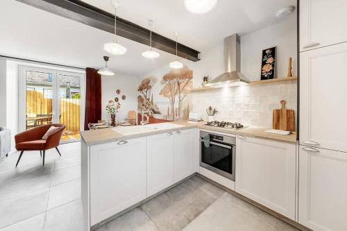 une cuisine avec des armoires blanches et une cuisinière dans l'établissement LE ROCHER- Belle maison de charme -Jardin/Parking, à Cancale