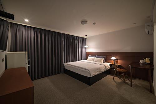 a hotel room with a bed and a table with a desk at 호텔 공감공간 부산역점 in Busan