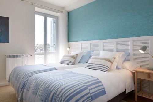 a bedroom with a large bed with a blue wall at H SUITE3B by Smiling Rentals in Hondarribia