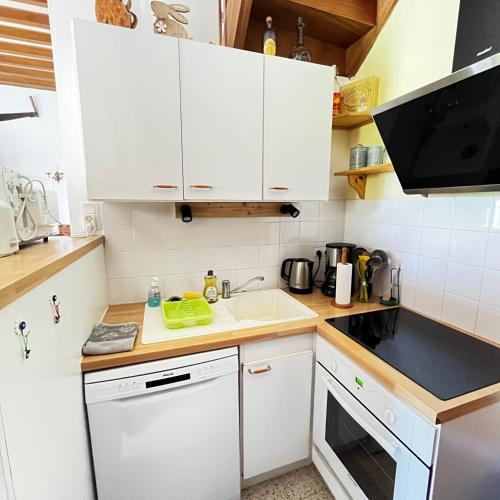 une petite cuisine avec des armoires blanches et un évier dans l'établissement Le Moulin de la Fosse Soucy 