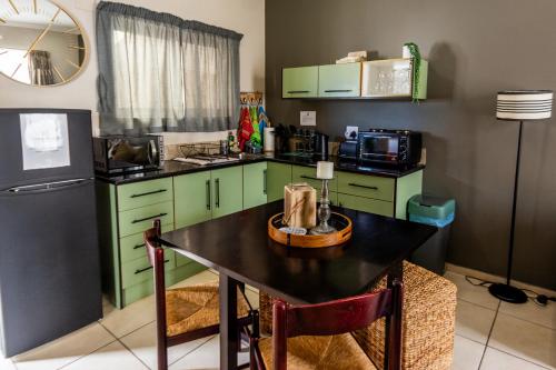 a kitchen with green cabinets and a table and a refrigerator at Long Beach Selfcatering Namibia in Langstrand