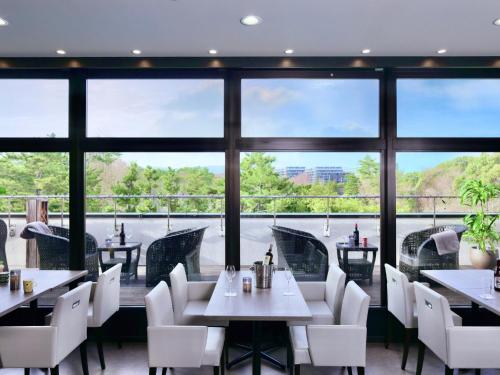 a restaurant with tables and chairs and large windows at Minamisenri Crystal Hotel - Vacation STAY 74035v in Suita