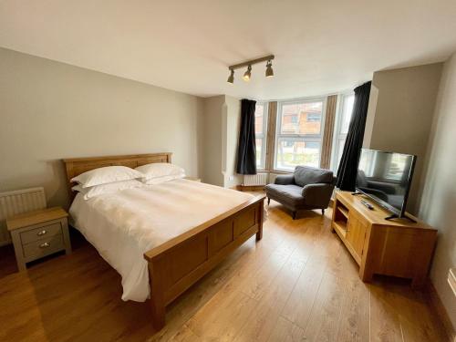 Salisbury Garden Apartment 3 beds 2 baths في Shrewton: غرفة نوم بسرير وتلفزيون وكرسي