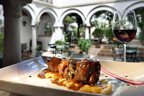 a white plate with food and a glass of wine at Eurostars Conquistador in Córdoba