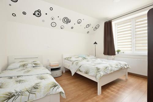 two beds in a white bedroom with palm trees on the wall at Penzion U Smrku Luleč in Lultsch