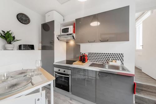 une cuisine avec un évier et un micro-ondes dans l'établissement L'Annexe - Plage 50 m et Remparts à 500 m, à Saint-Malo