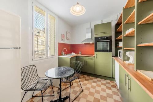 une cuisine avec des armoires vertes, une table et des chaises dans l'établissement Belle époque - Proche mail - Parking - 4 pers, à Rennes