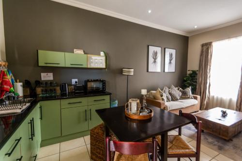 a kitchen and living room with green cabinets and a table at Long Beach Selfcatering Namibia in Langstrand