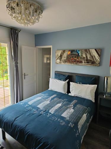 - une chambre avec un lit bleu et un lustre dans l'établissement le jardin d Eau, à Lamothe-Montravel