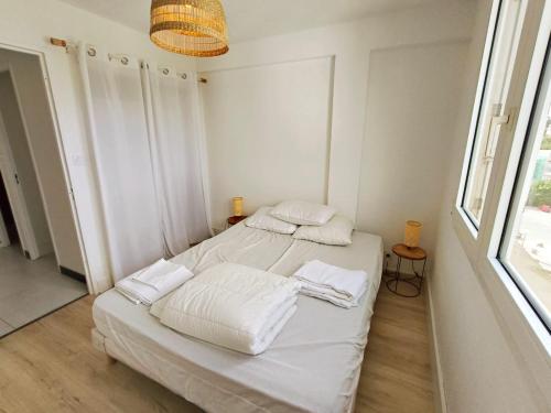 Cette chambre blanche dispose de deux lits et d'une fenêtre. dans l'établissement Cocon vue mer sur Presqu'île, à Hyères