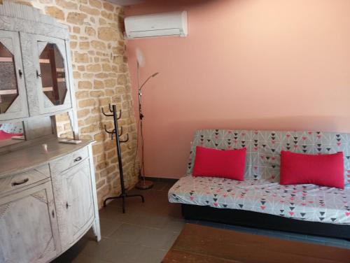 a room with a couch with two red pillows at Le cabanon au bord de l'Othain in Bazeilles-sur-Othain