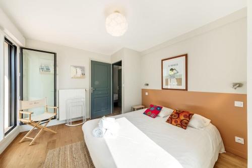 une chambre avec un grand lit blanc et une chaise dans l'établissement La Marinière - Terrasse et parking, proche plage, à Saint-Malo