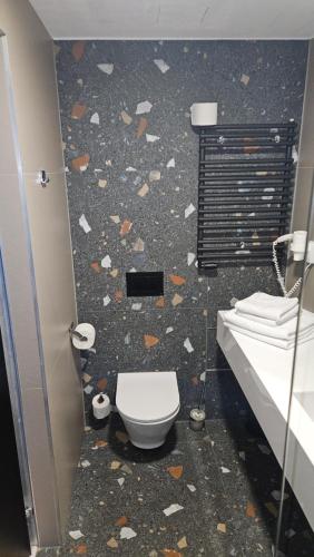 a bathroom with a toilet and a wall covered in debris at Biała Perła Residence Czarna Góra in Sienna