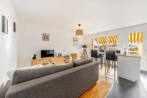 Il comprend un salon avec un canapé gris et une cuisine. dans l'établissement Le Frida - T2 rénové - Balcon- 500m centre, à Dinard