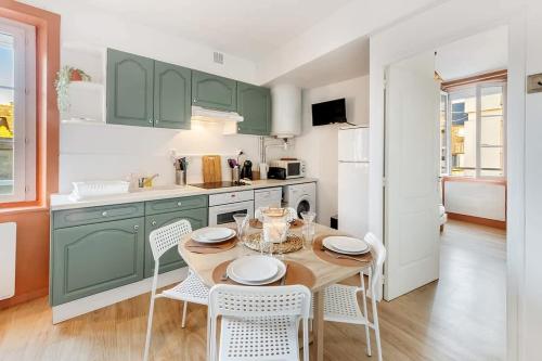 une cuisine avec des armoires vertes, une table et des chaises dans l'établissement Terracotta, appartement 1 chambre, 3 pers, à Saint-Malo