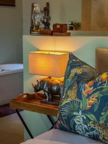 a lamp sitting on a table next to a pillow at Kambaku River Lodge in Malelane