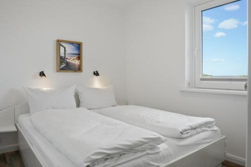 a white bedroom with two beds and a window at Gurtdeel Meerluft-Suite in Hörnum