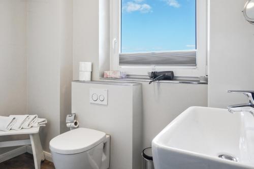 a white bathroom with a toilet and a window at Gurtdeel Meerluft-Suite in Hörnum